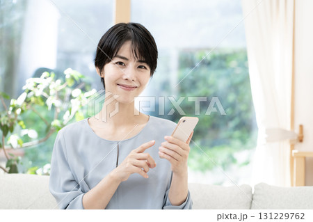 ソファーに座りスマートフォンを使う若い女性 ソファーに座りスマートフォンを使う若い女性 131229762
