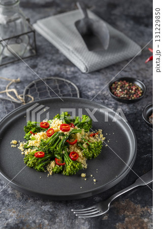 Delicious broccolini salad with toasted breadcrumbs and chili pepper flakes on black plate 131229850