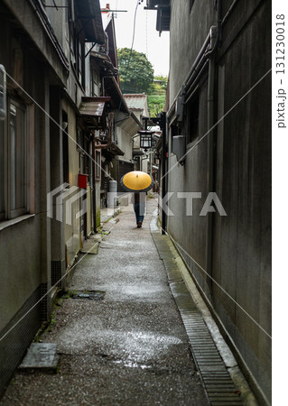 雨の日に傘をさして路地を歩く 131230018