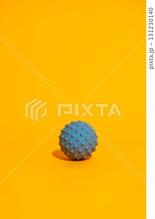Blue spiky massage ball on bright orange minimal fitness recovery concept with copy space Blue spiky massage ball on bright orange minimal fitness recovery concept with copy space 131230140