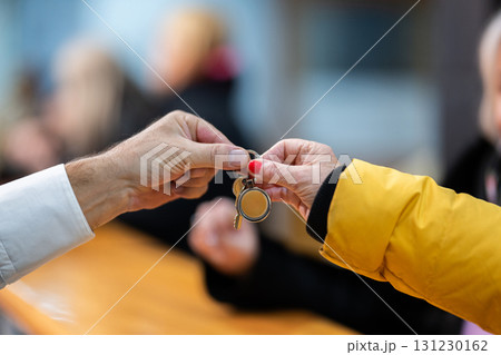 Detail of two people exchanging keys at a reception desk, symbolizing check in, service, hospitality, and property handover Detail of two people exchanging keys at a reception desk, symbolizing check in, service, hospitality, and property handover 131230162