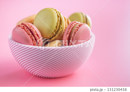 Different flavors of macarons. Colourful macaroons in bowl on pink background. Different flavors of macarons. Colourful macaroons in bowl on pink background. 131230438