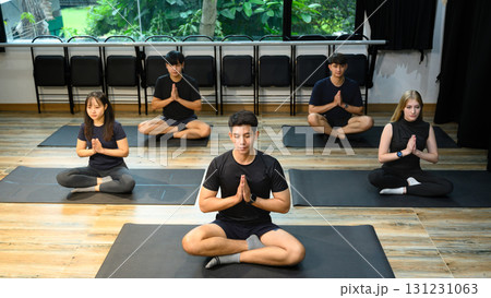 People in meditation posture during group yoga session, focusing on relaxation and balance 131231063