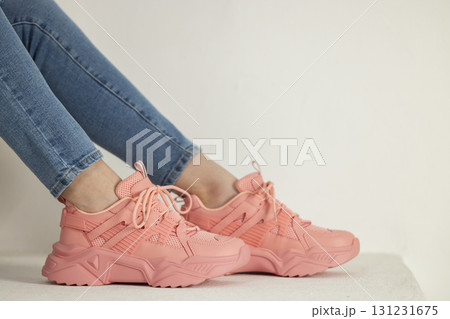 detail of sitting woman wearing pink trainers and jeans 131231675