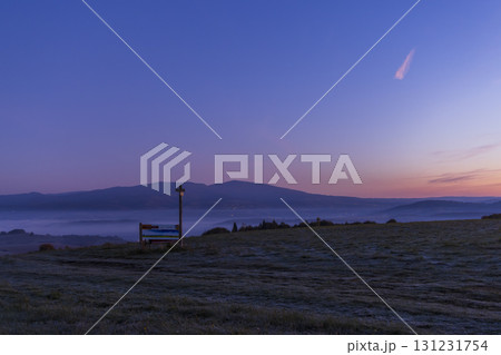 Peaceful sunrise view over misty Carpathian mountains with bench and cross 131231754