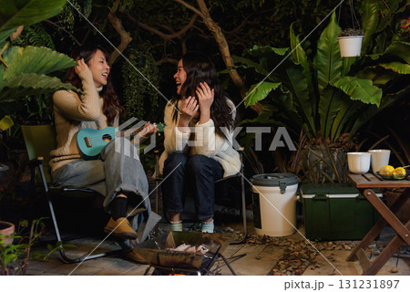 Winter camp outdoor friend people forest woman happy, enjoying music with ukulele and warm fire, sharing cheerful laughter moments in cold evening during beautiful winter season vacation. Winter camp outdoor friend people forest woman happy, enjoying music with ukulele and warm fire, sharing cheerful laughter moments in cold evening during beautiful winter season vacation. 131231897