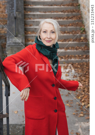Gray-haired woman of sixty years old in a red coat and a green scarf Gray-haired woman of sixty years old in a red coat and a green scarf 131233443