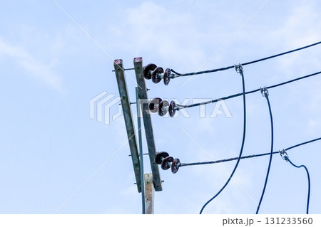 iron pole with wires and insulators high on a blue sky background 131233560