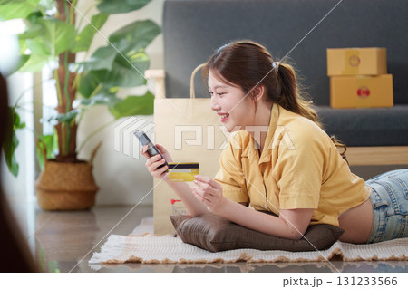 Online Shopping. Happy woman lying on the floor with smartphone and credit card. 131233566