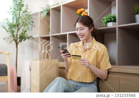 Digital Shopping. Young woman smiling while making an online purchase with smartphone and credit card. 131233568