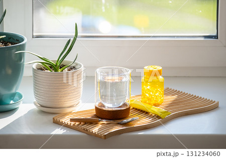 Glass of water near vitamin container and supplement stick pack on windowsill. Glass of water near vitamin container and supplement stick pack on windowsill. 131234060