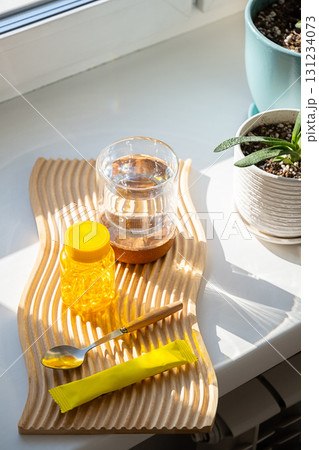 Yellow vitamins bottle, spoon, water glass, powder sachet on wooden board. Yellow vitamins bottle, spoon, water glass, powder sachet on wooden board. 131234073