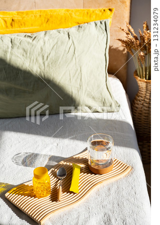 Glass of water with vitamin supplements on bed. Morning routine for health and wellness. Glass of water with vitamin supplements on bed. Morning routine for health and wellness. 131234079