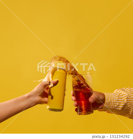 Golden beer splash between mockup can and glass on yellow background Golden beer splash between mockup can and glass on yellow background 131234292