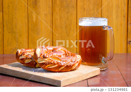 beer and pretzel on the table. celebration of oktoberfest. glass mug with cold beverage and baked salt snacks on the wooden background. rustic scene 131234981