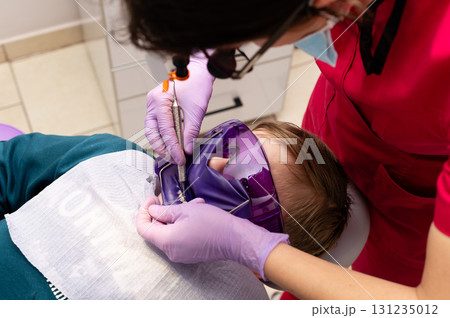 Young patient receiving dental care while wearing protective eyewear in a bright clinic setting during a routine check-up Young patient receiving dental care while wearing protective eyewear in a bright clinic setting during a routine check-up 131235012