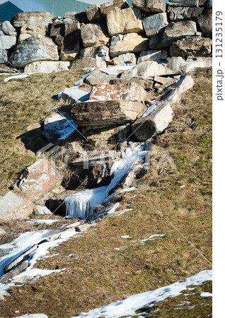 Boulders and snow melt create a natural waterway in a serene landscape during early spring in a mountainous region 131235179