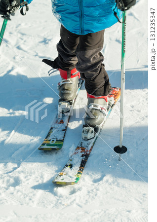 Skiing adventure on a snowy slope with vibrant gear and focused stance, capturing the thrill of winter sports in a picturesque mountainous landscape Skiing adventure on a snowy slope with vibrant gear and focused stance, capturing the thrill of winter sports in a picturesque mountainous landscape 131235347