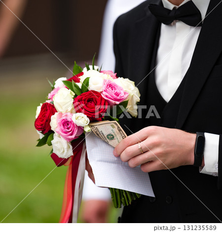 Groom holding wedding bouquet with hidden money. A unique and memorable wedding detail. 131235589