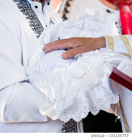 Gentle hands hold a baby during a christening ceremony. A moment of blessing and new beginnings. 131235757