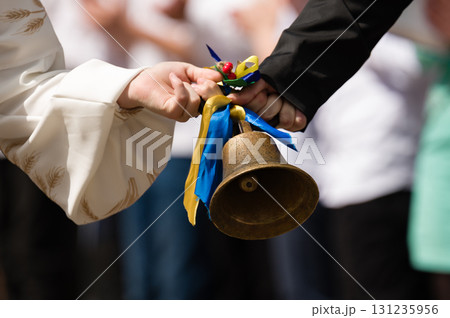 Two hands exchange a small bell adorned with blue and yellow ribbons. A ceremonial moment. 131235956