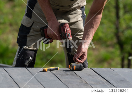 The craftsman uses a screwdriver to tighten the screws that secure the floor to the base of the gazebo. The craftsman uses a screwdriver to tighten the screws that secure the floor to the base of the gazebo. 131236264