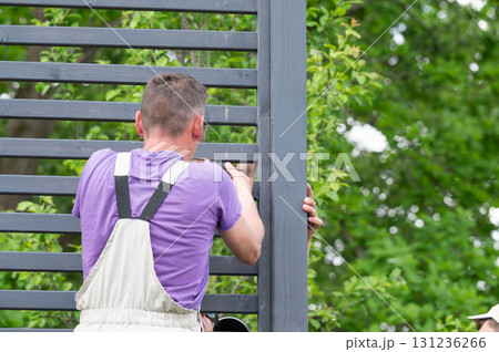Workers are installing a wall with wooden slats with a distance between them. Workers are installing a wall with wooden slats with a distance between them. 131236266