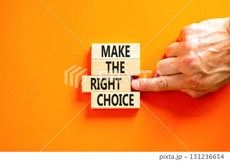 Make the right choice symbol. Concept words phrase Make the right choice on beautiful wooden blocks. Beautiful orange background. Businessman's hand. Business Make the right choice concept. Copy space 131236654