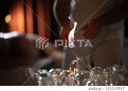 Close up of a traditional fire cupping therapy session with glass cups placed on a patients back and therapist using fire to create suction, promoting relaxation and healing. Close up of a traditional fire cupping therapy session with glass cups placed on a patients back and therapist using fire to create suction, promoting relaxation and healing. 131237057