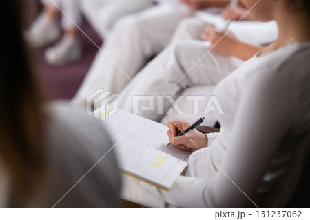 Close up of a student holding a pen and writing notes in a notebook during a professional training and education session in a wellness and therapy course Close up of a student holding a pen and writing notes in a notebook during a professional training and education session in a wellness and therapy course 131237062