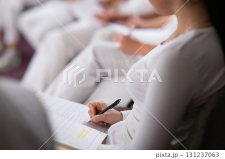 Close up of a student holding a pen and writing notes in a notebook during a professional training and education session in a wellness and therapy course 131237063