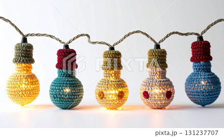 String of Decorative Crochet Light Bulbs with Warm Yellow Glow on White Background 131237707