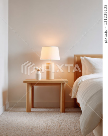 Cozy and tranquil bedroom interior with minimalist home decor. warm lamp on wooden nightstand creates peaceful mood next to simple bed furniture 131239138