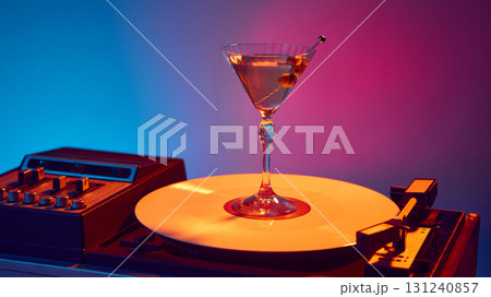 Martini glass with olives on glowing vinyl turntable in night bar style Martini glass with olives on glowing vinyl turntable in night bar style 131240857