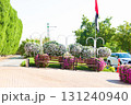 Peaceful park scene featuring wooden benches surrounded by vibrant flower displays and UAE flag stands in the background. Public park 131240940