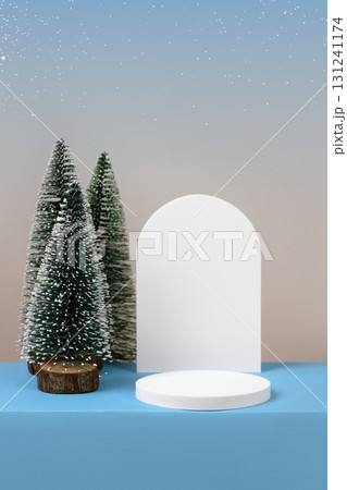 Winter background with cylindrical empty podium display for promotions and for showing product decorate. Stage pedestal or platform between Xmas trees on blue table. Merry Christmas celebration. Winter background with cylindrical empty podium display for promotions and for showing product decorate. Stage pedestal or platform between Xmas trees on blue table. Merry Christmas celebration. 131241174