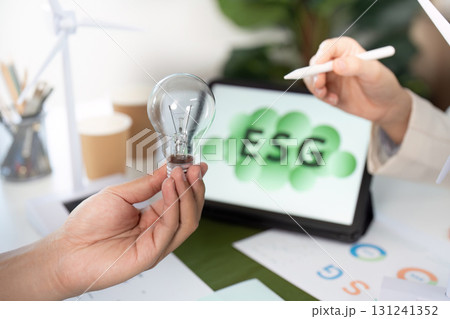 ESG analysis with light bulb and tablet in modern office setting ESG analysis with light bulb and tablet in modern office setting 131241352