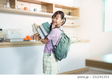 Back to School. Girl carrying books and backpack, smiling at home. 131241353