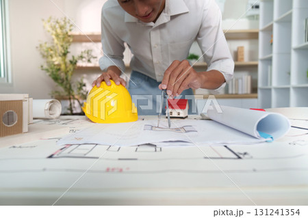 Engineer design. Young engineer using a compass on blueprints for architectural planning. Engineer design. Young engineer using a compass on blueprints for architectural planning. 131241354