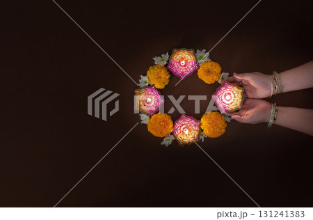 Hands Holding Diwali Candles Surrounded by Flowers Hands Holding Diwali Candles Surrounded by Flowers 131241383