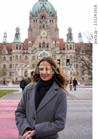 Smiling woman in coat near historic building 131241916