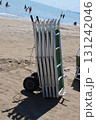 Stack of beach chairs on cart by the sea with people bathing 131242046