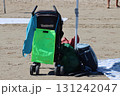 Baby stroller and bags parked on sandy beach under beach umbrella 131242047
