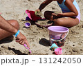 Father and daughter building sandcastles on beach with toys 131242050