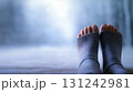 Bare toes peeking from cozy wool socks resting on cold snowy surface with blue winter background 131242981