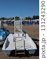 White pedal boat moored on sandy beach with slide and ladder, ready for summer fun 131243290