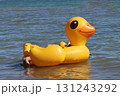 Tourist relaxing on inflatable yellow duck floating on blue water 131243292