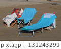 Beach towels drying on deckchairs on sandy beach 131243299