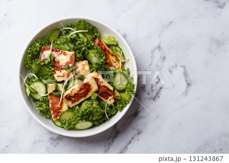 Cucumbers, sprouts and green leaves salad with fried halloumi. 131243867