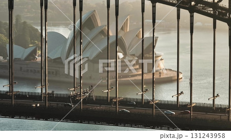 Australia, Sydney: Cars driving Sydney Harbour Bridge at sunrise, framing Sydney Opera House in background, creating stunning view of Australian landmarks. Modern architecture and urban transportation Australia, Sydney: Cars driving Sydney Harbour Bridge at sunrise, framing Sydney Opera House in background, creating stunning view of Australian landmarks. Modern architecture and urban transportation 131243958